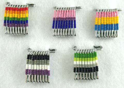 Safety pins with beads arranged in pride flag patterns