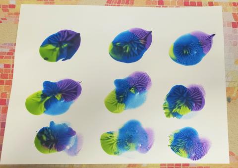 Splotches of blue, purple and green paint in three rows of three on a white background.