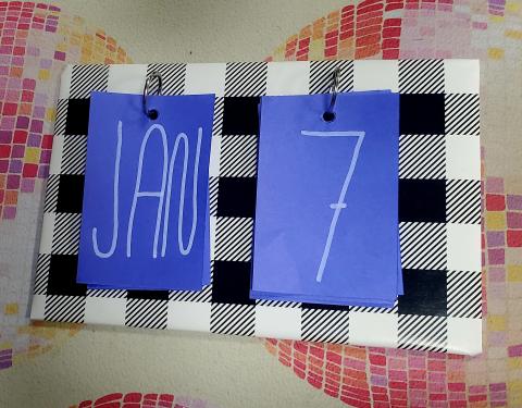 Calendar showing Jan 7 in blue on black and white plaid background